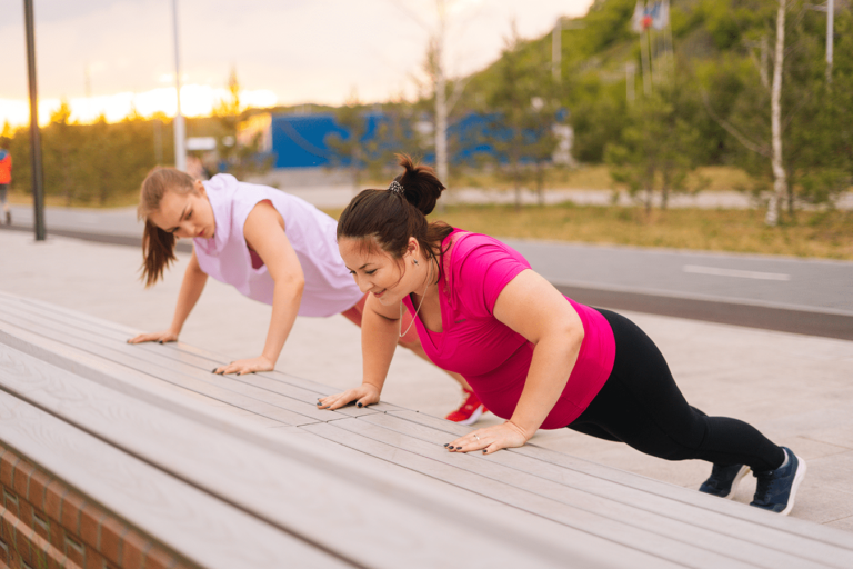 two women doing pushups outside