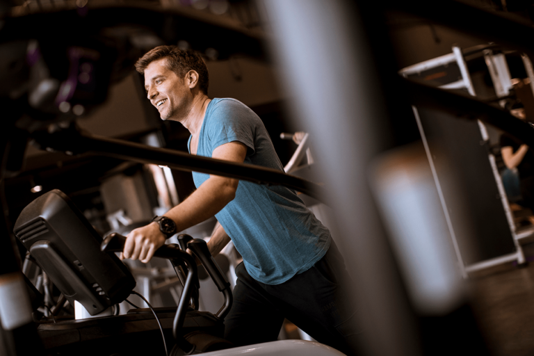 man exercising elliptical in gym