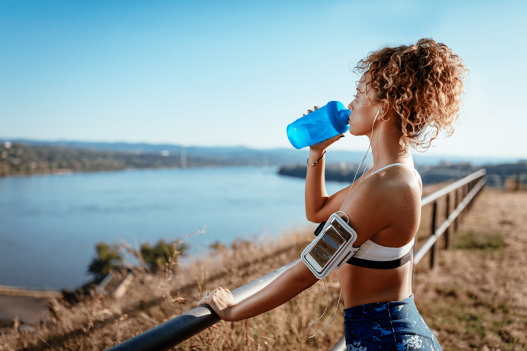 woman on an outside run drinking water